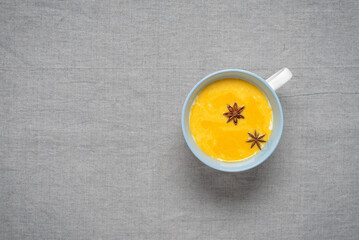 Golden milk with turmeric and spices in a cup. Cold and flu drink. Top view, selective focus. Gray...