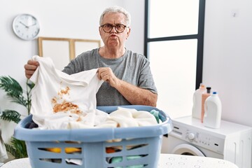 Senior caucasian man holding dirty t shirt with stain looking at the camera blowing a kiss being lovely and sexy. love expression.