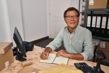 Middle age man ecommerce business worker writing on book at office