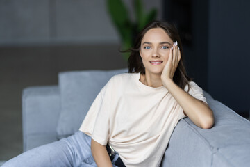 Smiling young woman wearing casual clothes relaxing on a couch at home