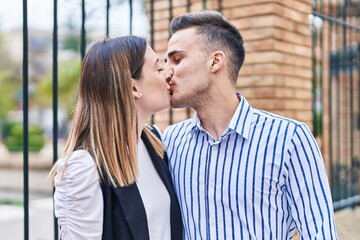 Man and woman couple hugging each other kissing at street