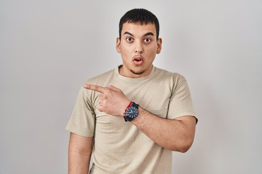 Young arab man wearing casual t shirt surprised pointing with finger to the side, open mouth amazed expression.
