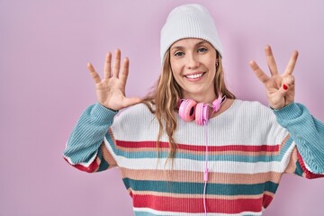 Fototapeta na wymiar Young blonde woman standing over pink background showing and pointing up with fingers number eight while smiling confident and happy.