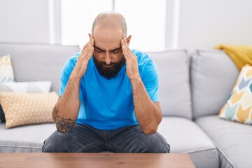Young bald man stressed sitting on sofa at home