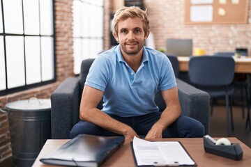 Young man business worker smiling confident sitting on sofa at office