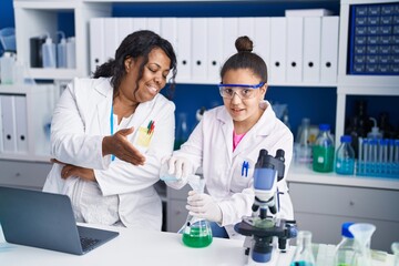 Mother and daughter scientists measuring liquid at laboratory
