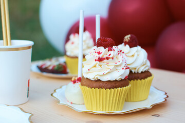 Muffin with cream decorated with raspberries. cake pops in the background. Dessert table detail