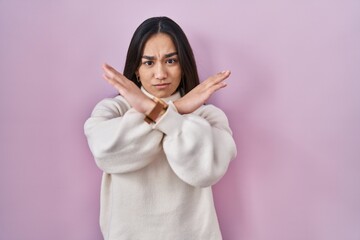 Fototapeta premium Young south asian woman standing over pink background rejection expression crossing arms doing negative sign, angry face