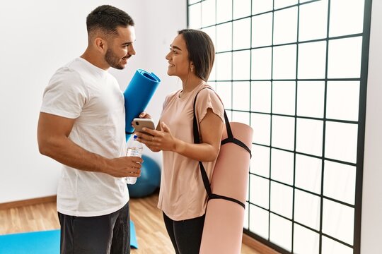Latin man and woman couple wearing sportswear using smartphone at sport center