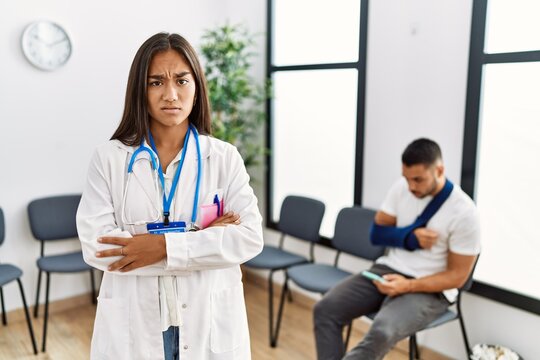 Young asian doctor woman at waiting room with a man with a broken arm skeptic and nervous, disapproving expression on face with crossed arms. negative person.