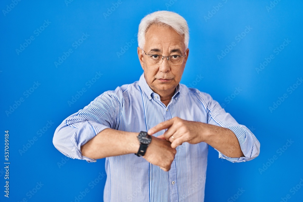 Sticker Hispanic senior man wearing glasses in hurry pointing to watch time, impatience, upset and angry for deadline delay