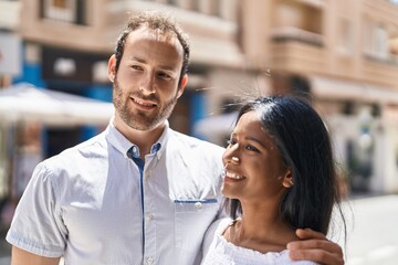 Man and woman interracial couple hugging each other at street