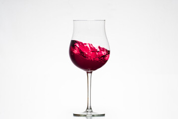 glass with red wine in motion, tulip glass, oenology, wineries, white background.
