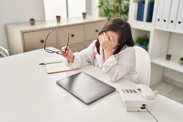 Down syndrome woman wearing doctor uniform stressed working at clinic