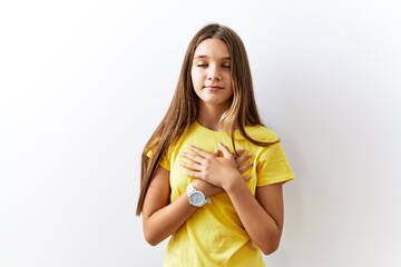 Young brunette teenager standing together over isolated background smiling with hands on chest with closed eyes and grateful gesture on face. health concept.