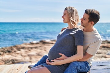 Man and woman couple hugging each other expecting baby at seaside