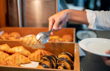 Man's hands holding bread with tongs in a bread shop, croissants, bread, breakfast