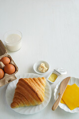 Croissant with varius ingredient on white wood background.