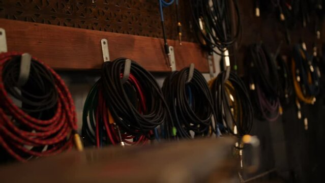 Wires and cables for musical instruments hang on the wall in an analog recording studio