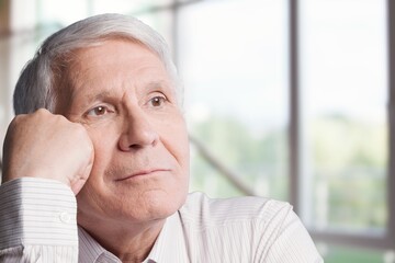 Serious old man looks in the window with nostalgia