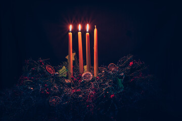 three advent candles burning on advent wreath