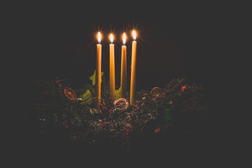 four advent candles burning on advent wreath