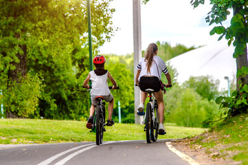 Naklejka premium A boy and a girl ride bicycles in a city park 