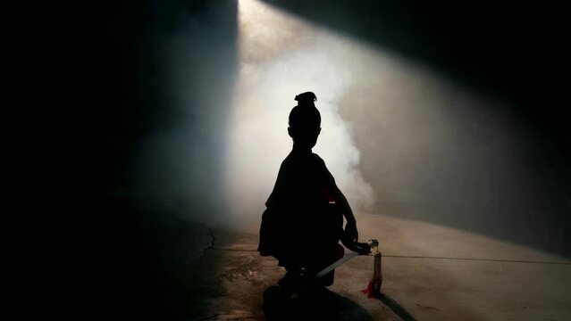silhouette of child samurai with katana against bright magic light and smoke, japanese culture