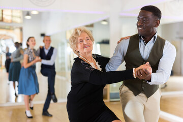 Woman pensioner with african man practising charleston