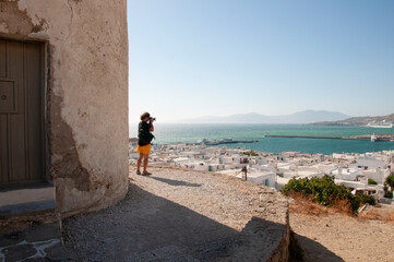 A man photographs the view next to a traditional windmill in the village of Chora, Mykonos island,...