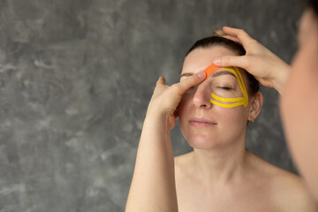 Cropped photo of therapist doctor woman applying orange yellow kinesio tapes on forehead of...