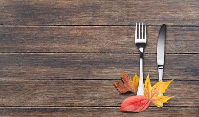 Colored autumn leaves with fork and knife on the desk