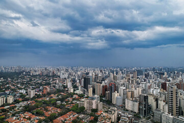 Fototapeta na wymiar Rainy day in the Jardins neighborhood located in the city of São Paulo, capital. Dark clouds, buildings, cars, trees and pedestrians circling.