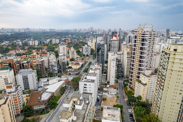 Fototapeta na wymiar Rainy day in the Jardins neighborhood located in the city of São Paulo, capital. Dark clouds, buildings, cars, trees and pedestrians circling.