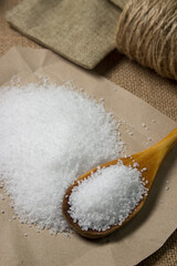 Large rock sea salt on a brown background. Wooden spoon full of salt
