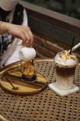 Closeup of Iced Caramel Macchiato at the coffee shop, Caramel Macchiato is a classic macchiato beverage. It consists of vanilla syrup, espresso, steamed milk, foam, and caramel drizzle