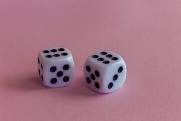 Two white plastic dice on a neutral pink background.