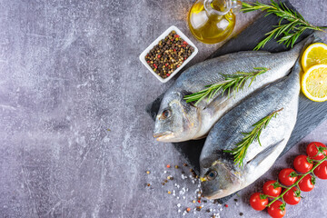 Dorado fish on gray concrete background with copy space. Sea food with ingredients for cooking. Delicacy spices and vegetables. Banner, header, background for menu and restaurant recipe