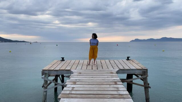 Woman standing on jetty watching the sea