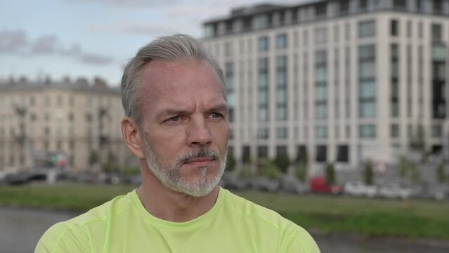 Mature athlete standing in city looking thoughtful