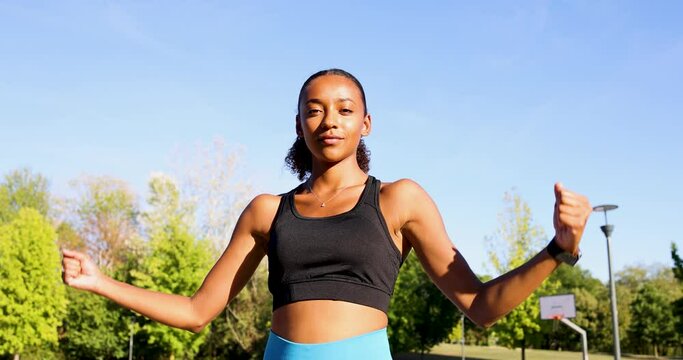 Young woman flexing muscles in park