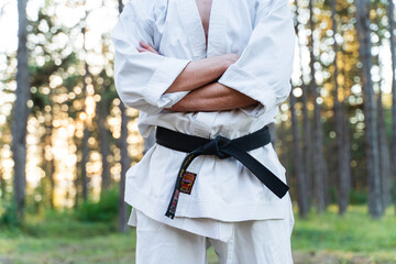 A young man doing karate in the forest training strength pose meditation 