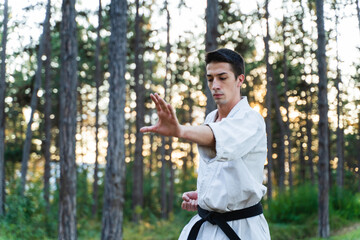 A young man doing karate in the forest training strength pose meditation 