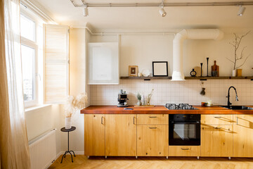 Stylish kitchen interior of modern apartment made in white and beige tones with wooden kitchen front and floor