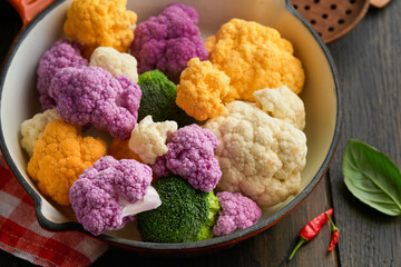 Colorfu cauliflower. Cauliflower cut into small pieces in red iron panon old wooden rustic background. Food cooking and agricultural harvest concept or background.