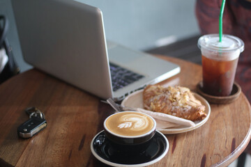 A cup of latte art and laptop on the table
