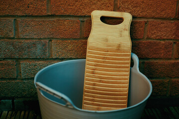 a bamboo laundry board in a rubber tub against a brick wall - 537035371