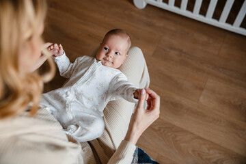 Young white mother wearing housecoat playing with her baby