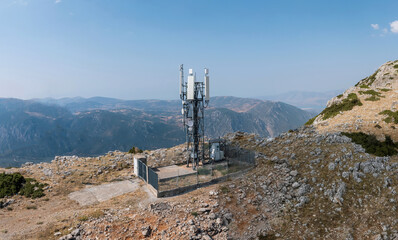 Cell tower. Mobile phone antenna aerial view. Rocky mountain and blue sky
