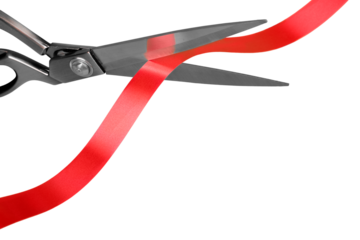 Scissors cutting red ribbon, close-up view on white background